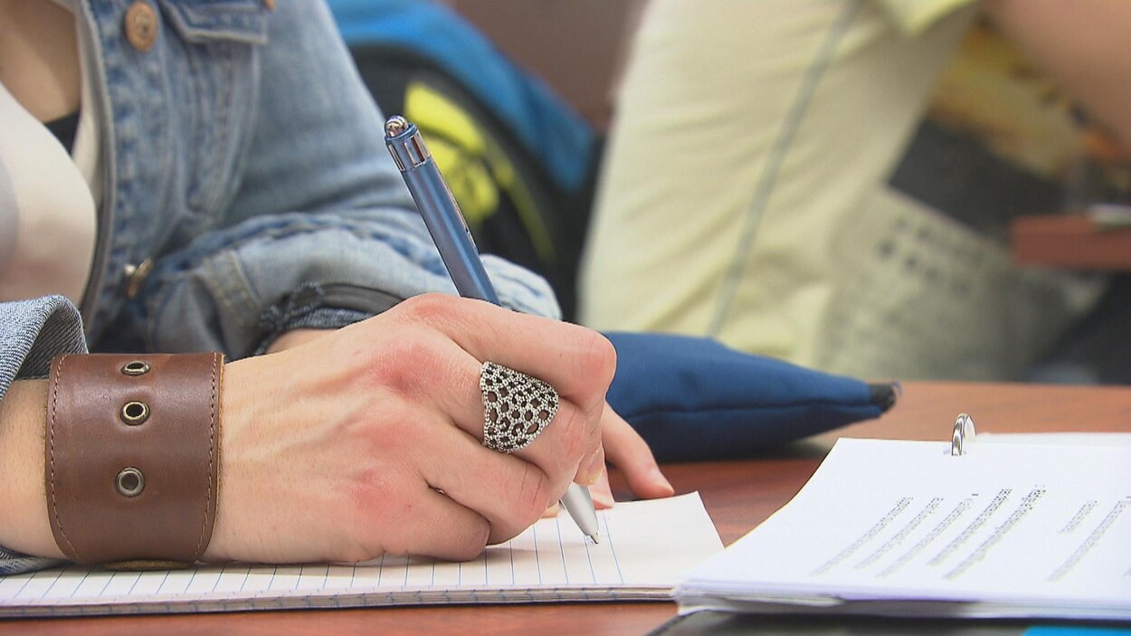 Une étudiante inscrit des notes sur une feuille.