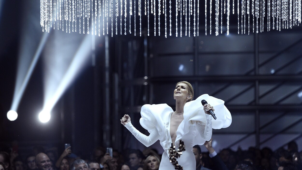 Céline Dion vêtue d'une robe blanche sous un immense lustre en verre. Céline Dion vêtue d'une robe blanche sous un immense lustre en verre.