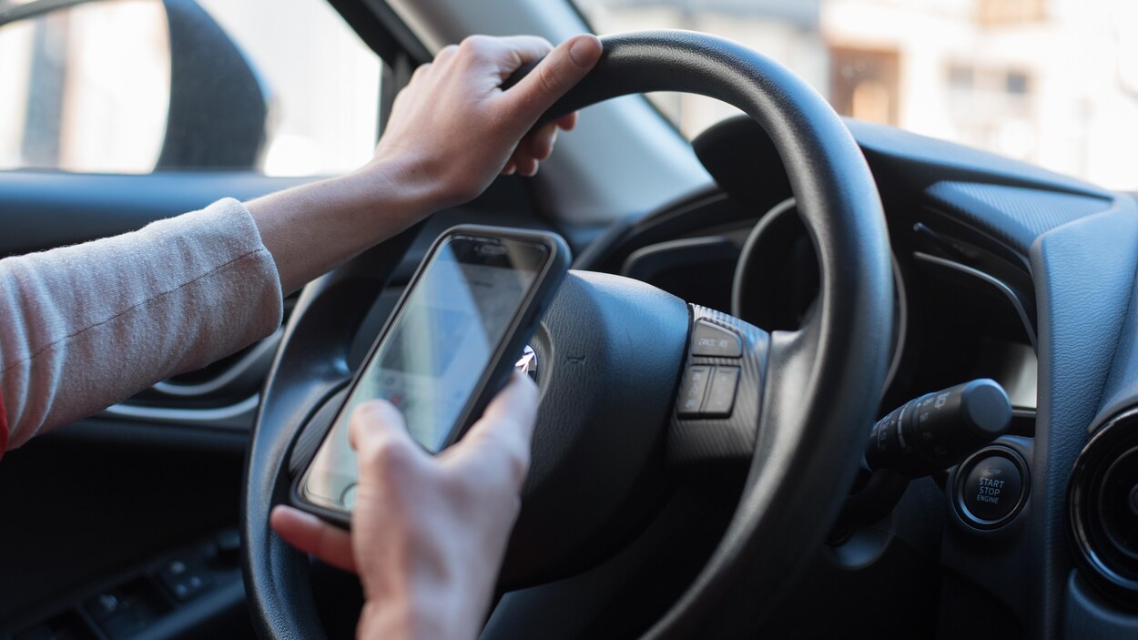 Une personne utilisant son cellulaire en conduisant.