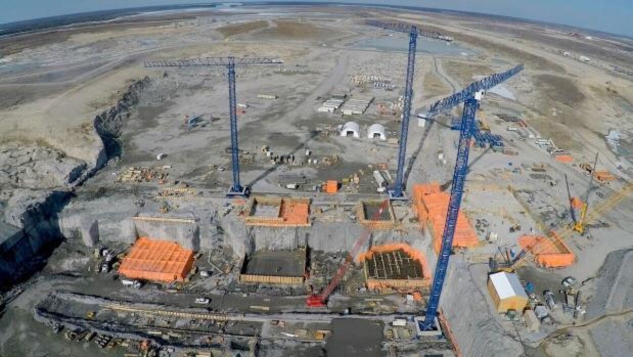 Vue aérienne d'un chantier de construction sur lequel se trouvent, entre autres, trois grues.