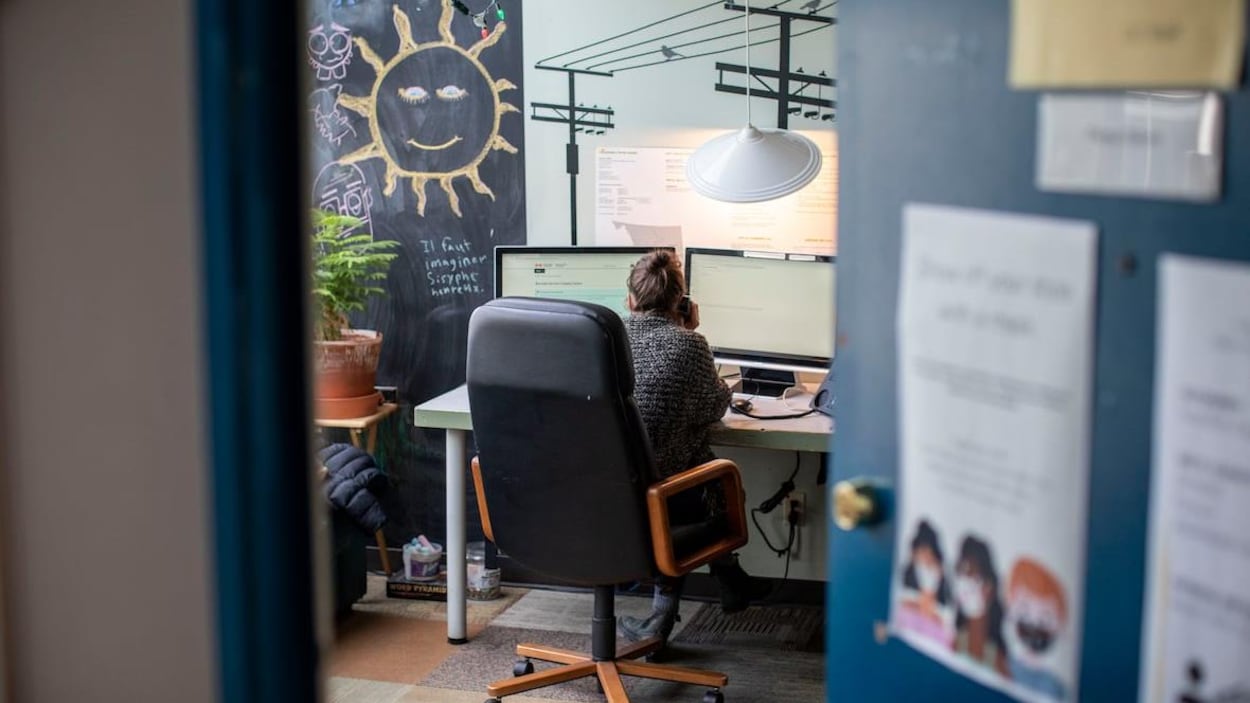 Une femme, que l'on aperçoit de dos, parle au téléphone dans un bureau d'un centre de crise à Vancouver.