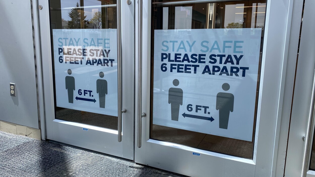 Une affiche à l'entrée d'un centre commercial demande aux clients de se tenir à deux mètres les uns des autres.