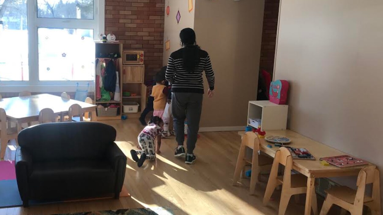 Vue de dos de plusieurs enfants d’âges préscolaires et d’une éducatrice dans une grande salle de jeu du Centre éducatif Gard'Amis..