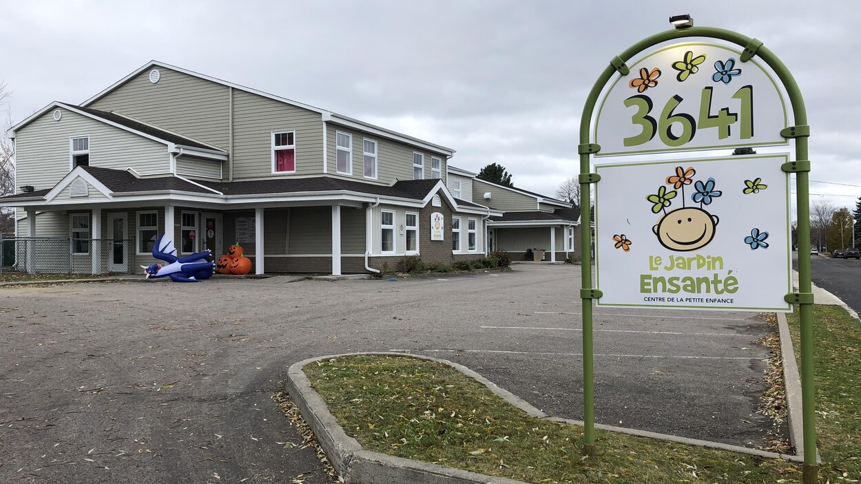 Une affiche sur laquelle est écrit 3641 Le Jardin Ensanté, devant un immeuble gris.