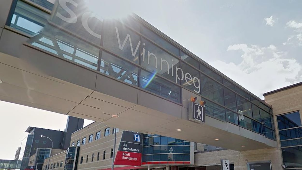 Une passerelle majoritairement en verre qui se connecte au deuxième étage d'un édifice hospitalier.