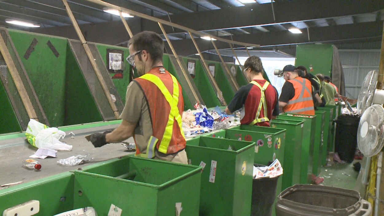Des hommes travaillent sur une chaîne dans le centre de triage.