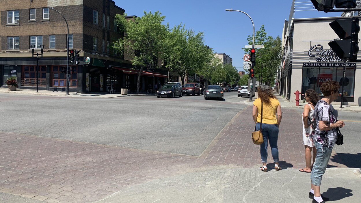 Des personnes attendent de traverser sur un coin de rue du centre-ville.