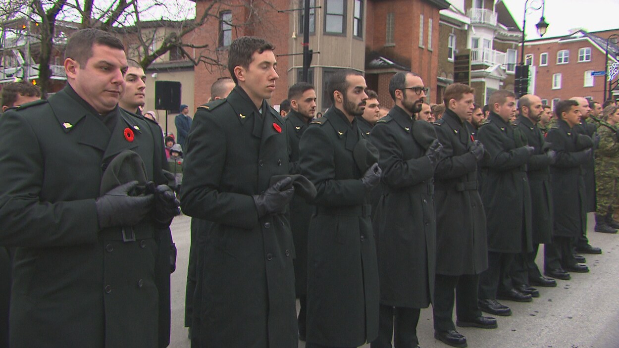 Des membres des Forces armées se recueillent avec leur chapeau en main.