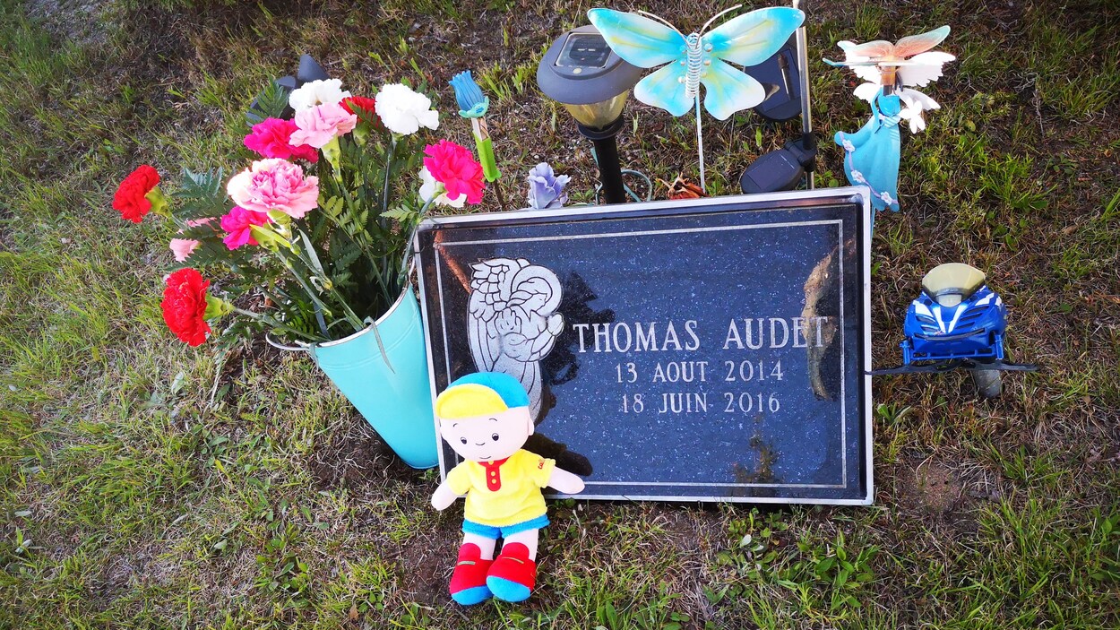 La tombe avec des fleurs et des jouets