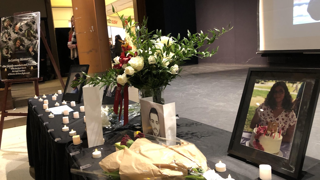 Des photos des victimes déposées sur une table sont entourées de lampions allumés et de bouquets de fleurs