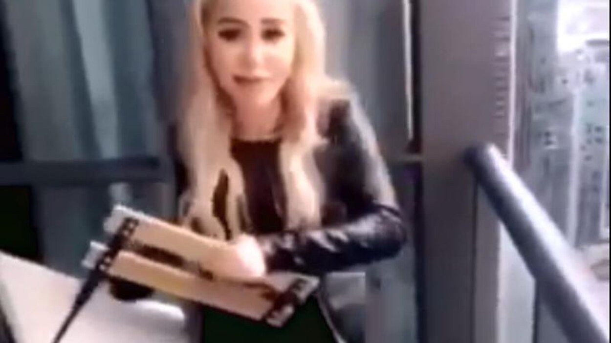 Photo d'une femme aux cheveux blonds qui tient une chaise pliante dans les mains.