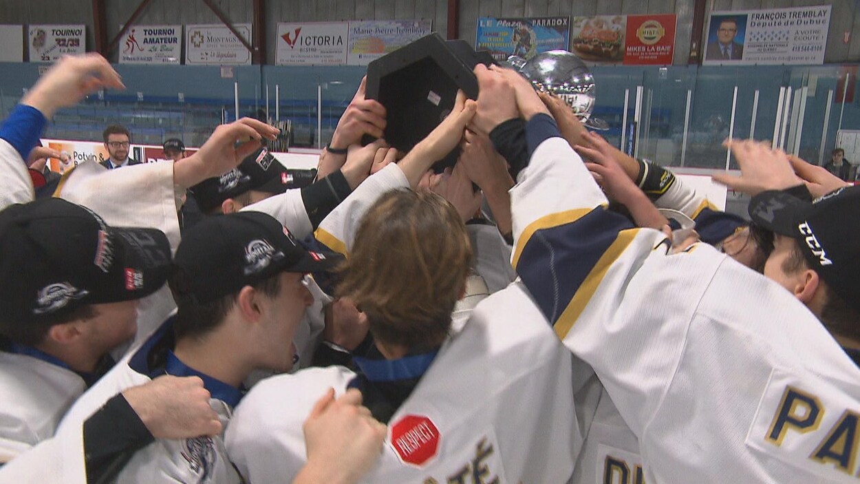 Des joueurs de hockey se massent autour d'un trophée.