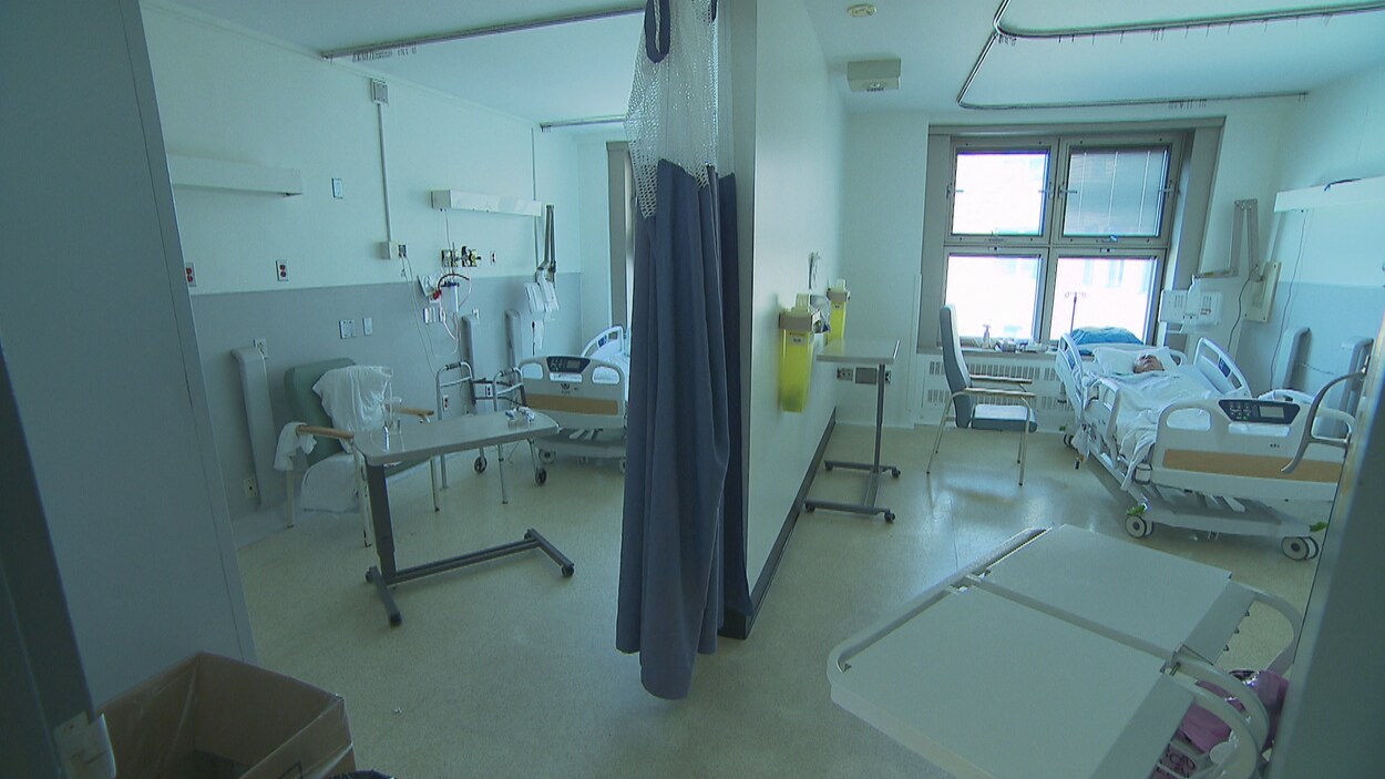 Un homme est couché dans un lit d'hôpital. L'autre lit est vide.