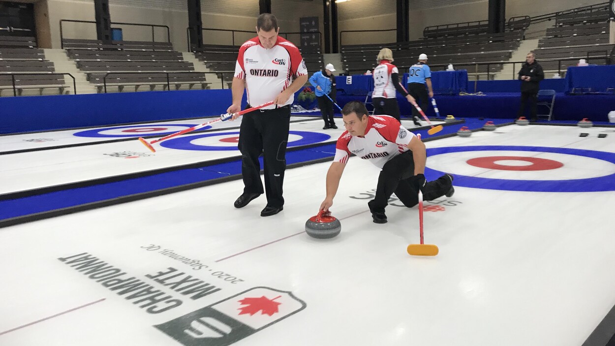 Des joueurs de curling sur une surface de jeu.