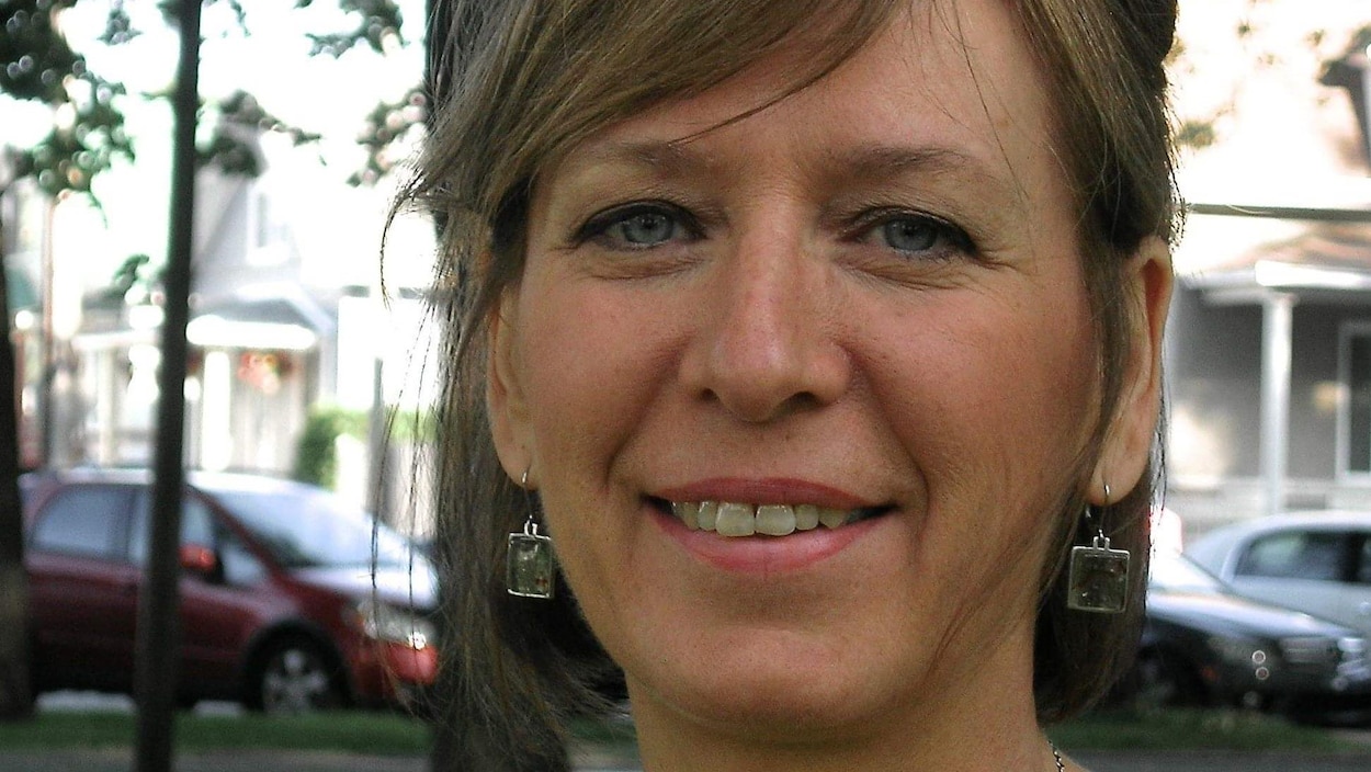 Portrait en couleur de l'autrice Chantal Fortier, en extérieur. Elle porte des boucles d'oreilles et un collier. On aperçoit en arrière-plan des arbres, des maisons et des voitures stationnées.