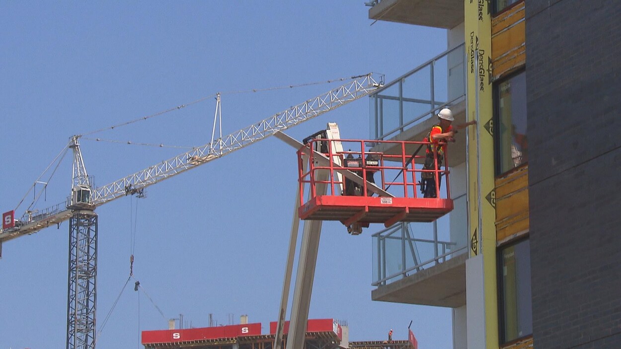 Homme dans les airs près d'un bâtiment et d'une grue.