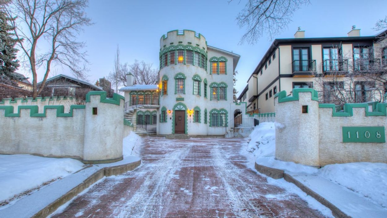 Une grande maison verte et blanche en hiver.