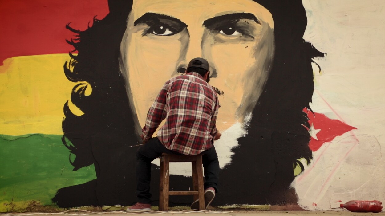 Un homme peinture le Che devant un mur.