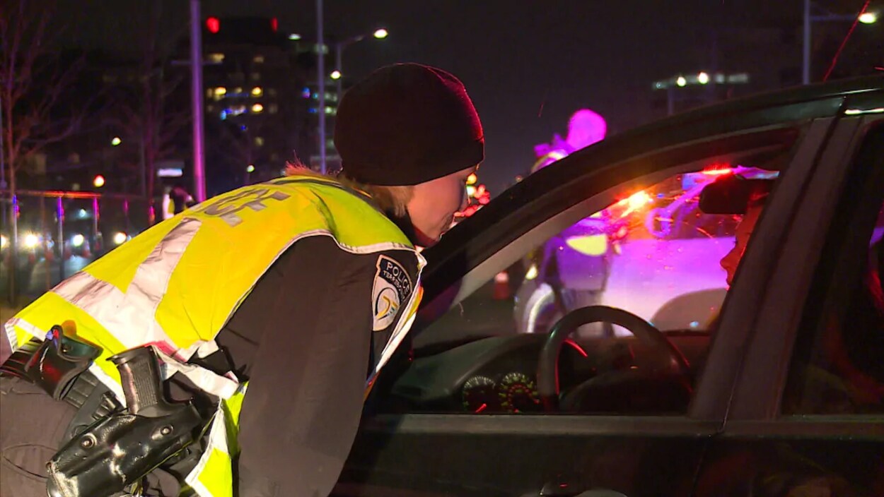 Un agent de la Gendarmerie royale du Canada se penche vers un véhicule dont la fenêtre est ouverte.