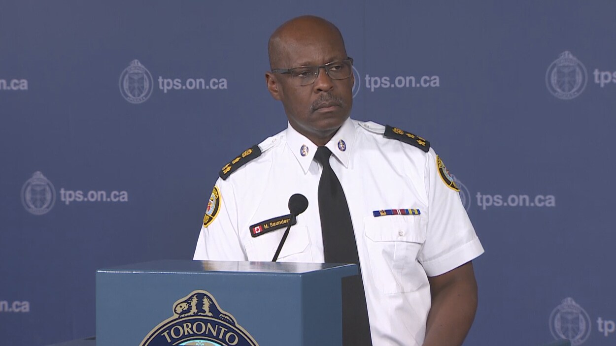 Photo d'un homme portant un uniforme de police blanc se tenant debout derrière un podium.