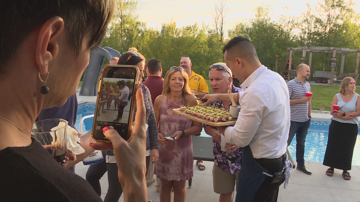 Le chef sushi Vinh Tran distribue des sushis pressés aux invités sur une terrasse. Une femme prend une photo.