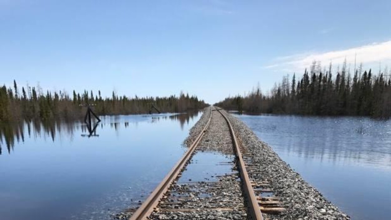 Un chemin de fer est à demi immergé dans l'eau, qui entoure la voie. Un chemin de fer est à demi immergé dans l'eau, qui entoure la voie.