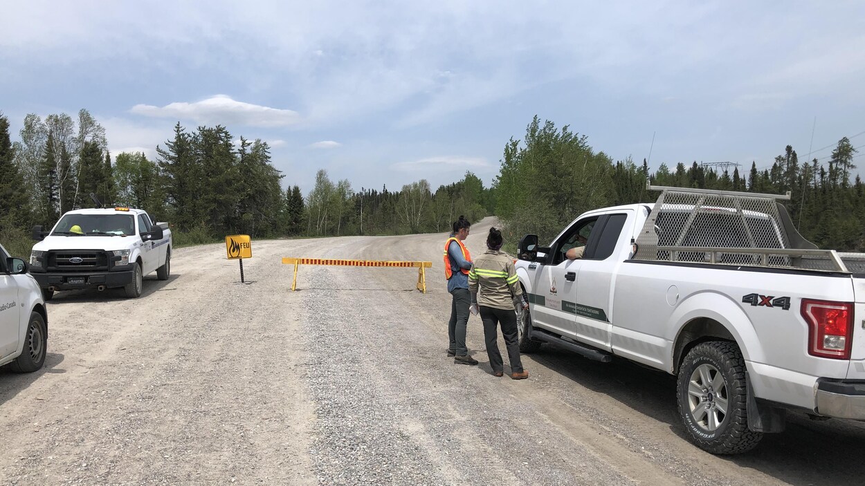 Des véhicules arrêtés et deux personnes qui discutent avec un conducteur.