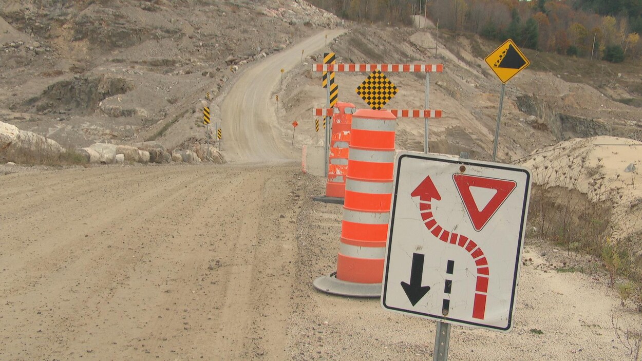 Un chemin de terre avec des panneaux de signalisation.
