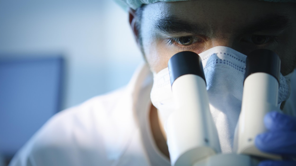 Un scientifique regarde dans un microscope.