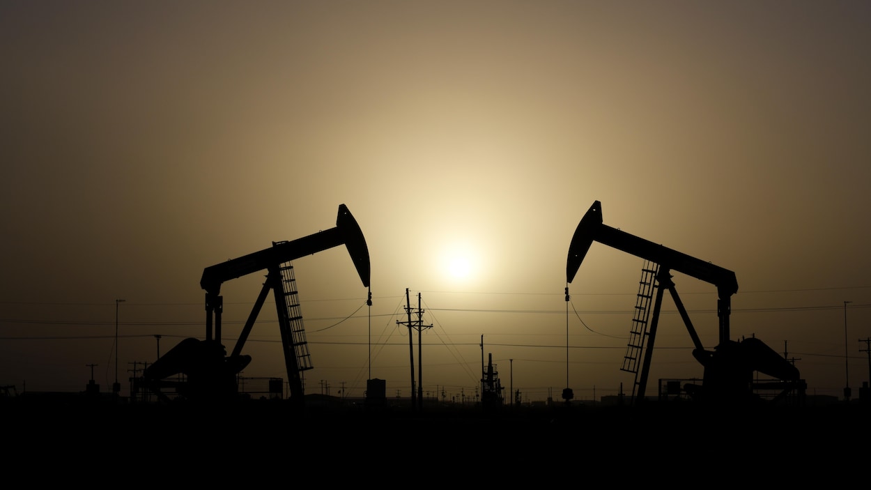 Des chevalets de pompage d'une entreprise pétrolière sont en opération au coucher du soleil.