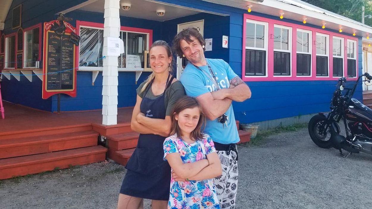 Les propriétaires du casse-croûte Chez Ginette et leur fille devant leur établissement fraîchement peint en bleu et rose.