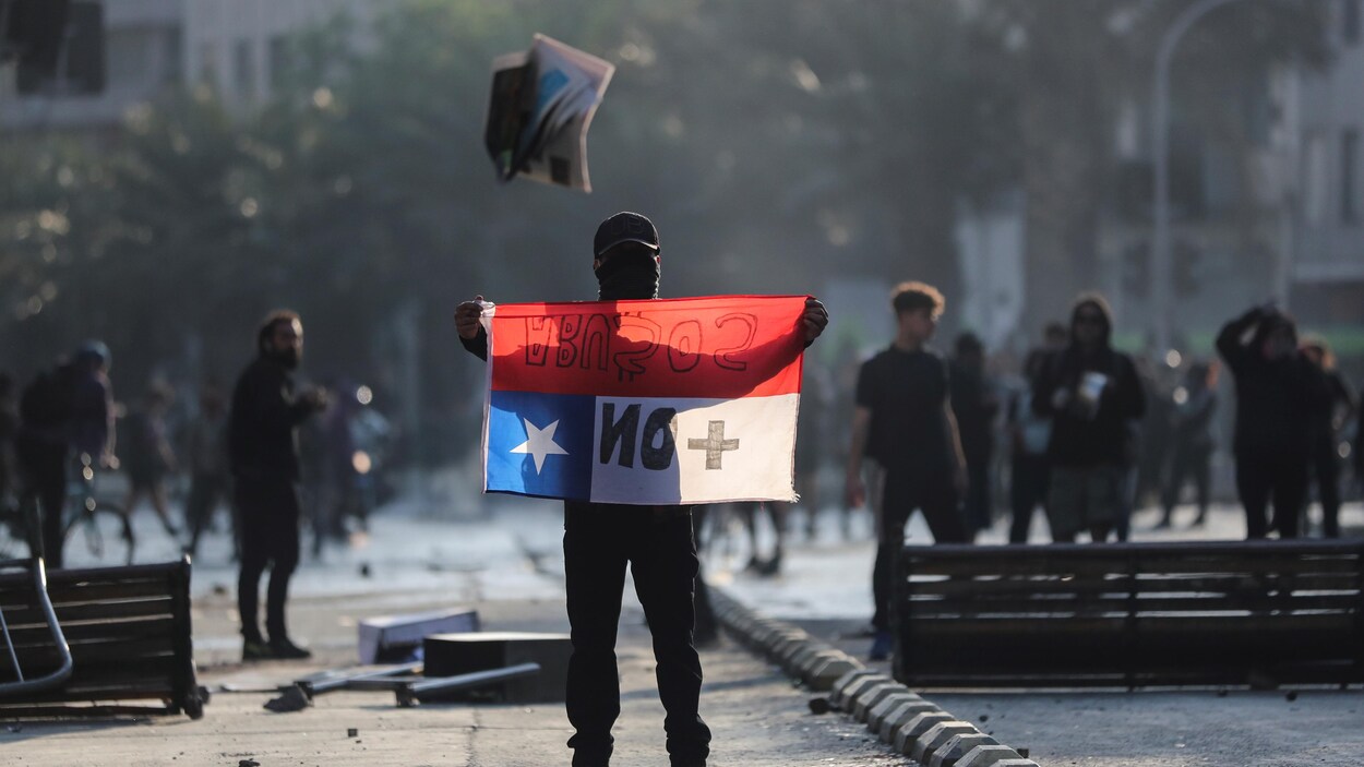 Un manifestant tient en main le drapeau du Chili.