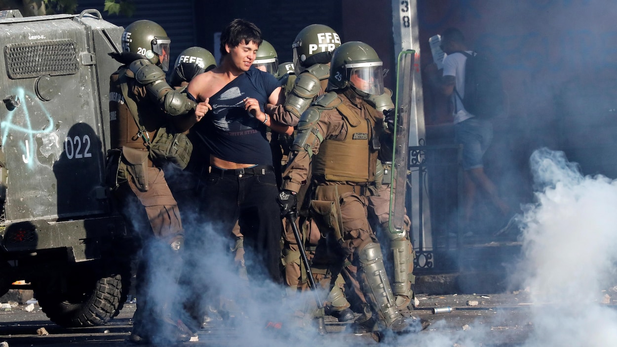 Des forces de sécurité interpellent un manifestant dans la rue.