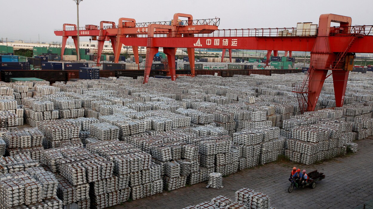 Les travailleurs se promènent avec leur petit triporteur à travers des milliers de lingots d'aluminium. Les travailleurs se promènent avec leur petit triporteur à travers des milliers de lingots d'aluminium.