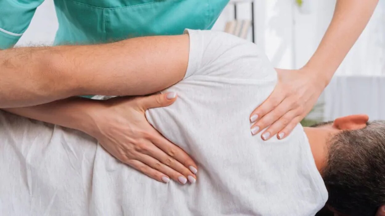 Une femme effectue un traitement de chiropratique sur un patient.