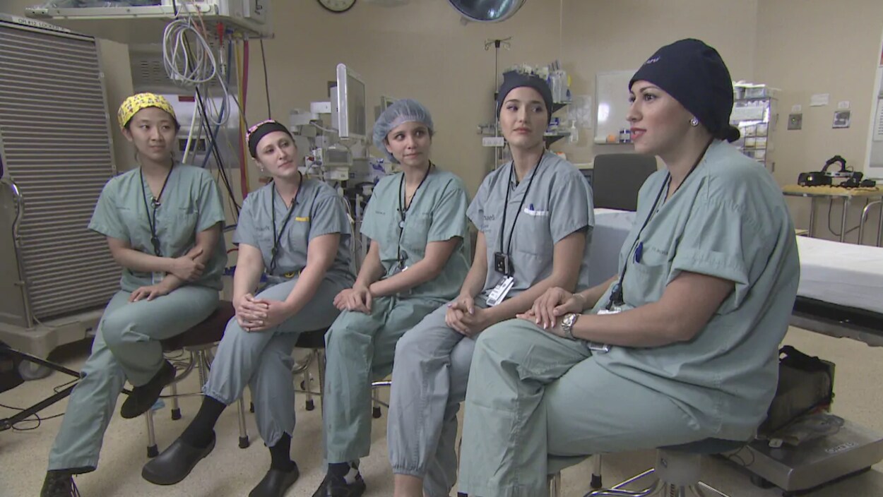 Cinq résidentes en chirurgie sont assises, habillées de leur blouse de médecin.