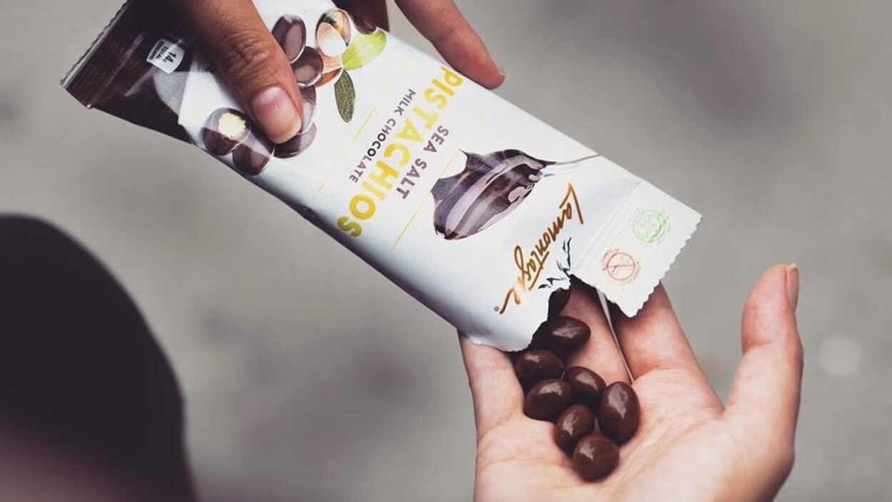 L'un des produits de Chocolat Lamontagne, des pistaches au chocolat et sel de mer. On voit ici quelqu'un se servir dans un paquet déjà ouvert.