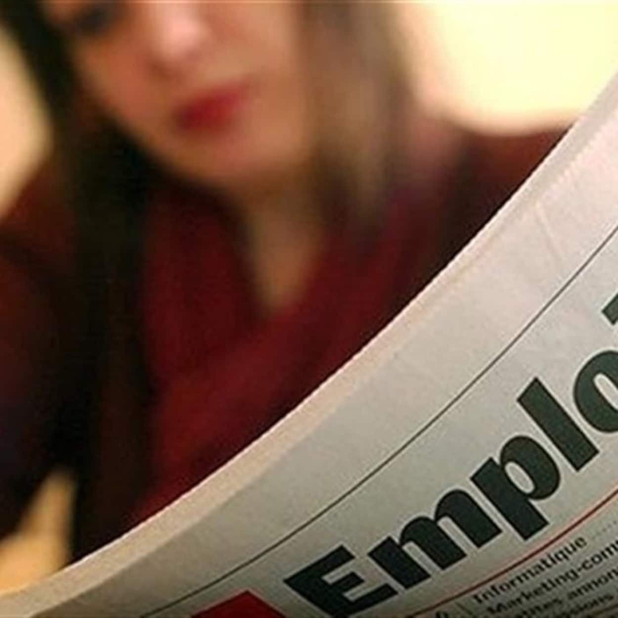 Femme lisant un journal pour de la recherche d'emplois
