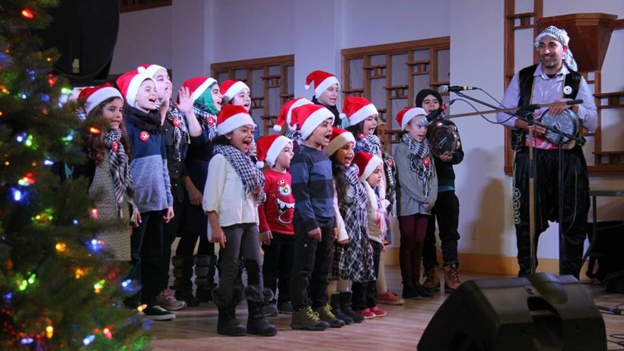 Des enfants chantent tout sourire sur la scène d'un centre communautaire montréalais. Des enfants chantent tout sourire sur la scène d'un centre communautaire montréalais.
