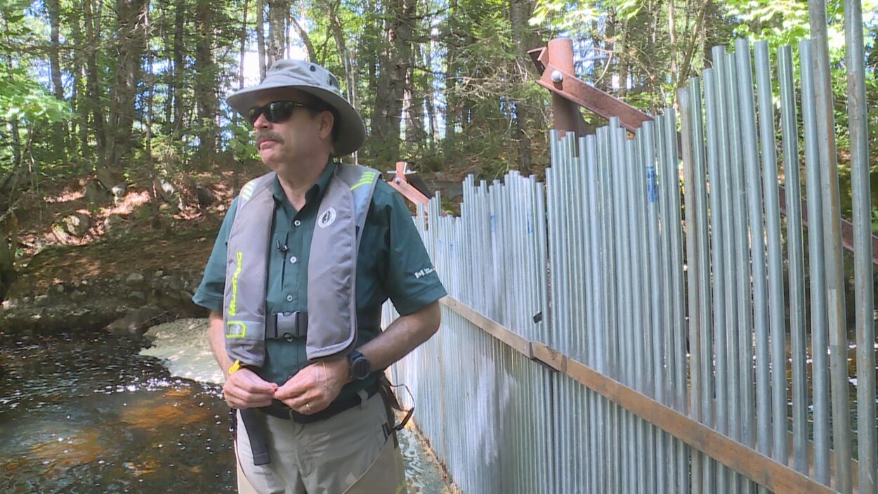 Chris McCarthy devant la clôture posée sur la rivière. Chris McCarthy devant la clôture posée sur la rivière.