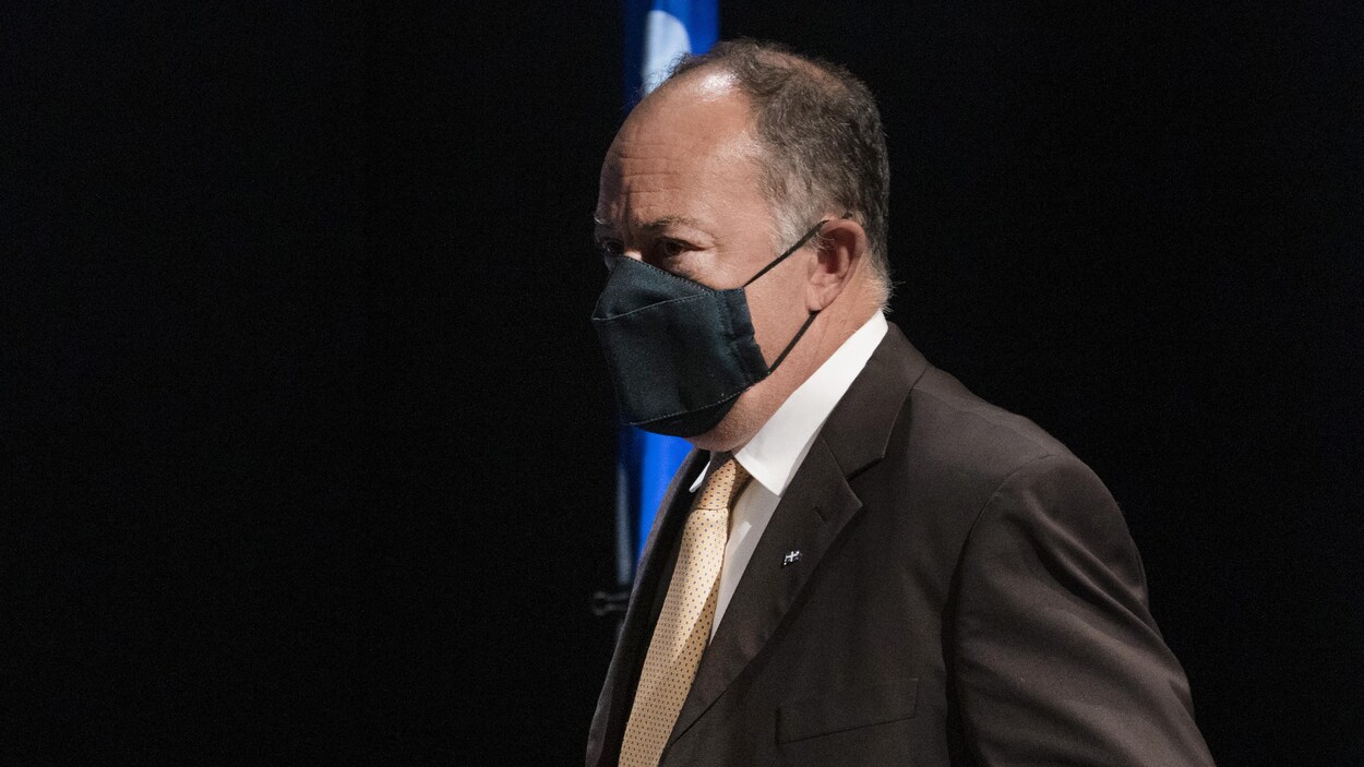 Le ministre de la Santé et des Services sociaux, Christian Dubé, debout et portant un masque à son arrivée à la conférence de presse.