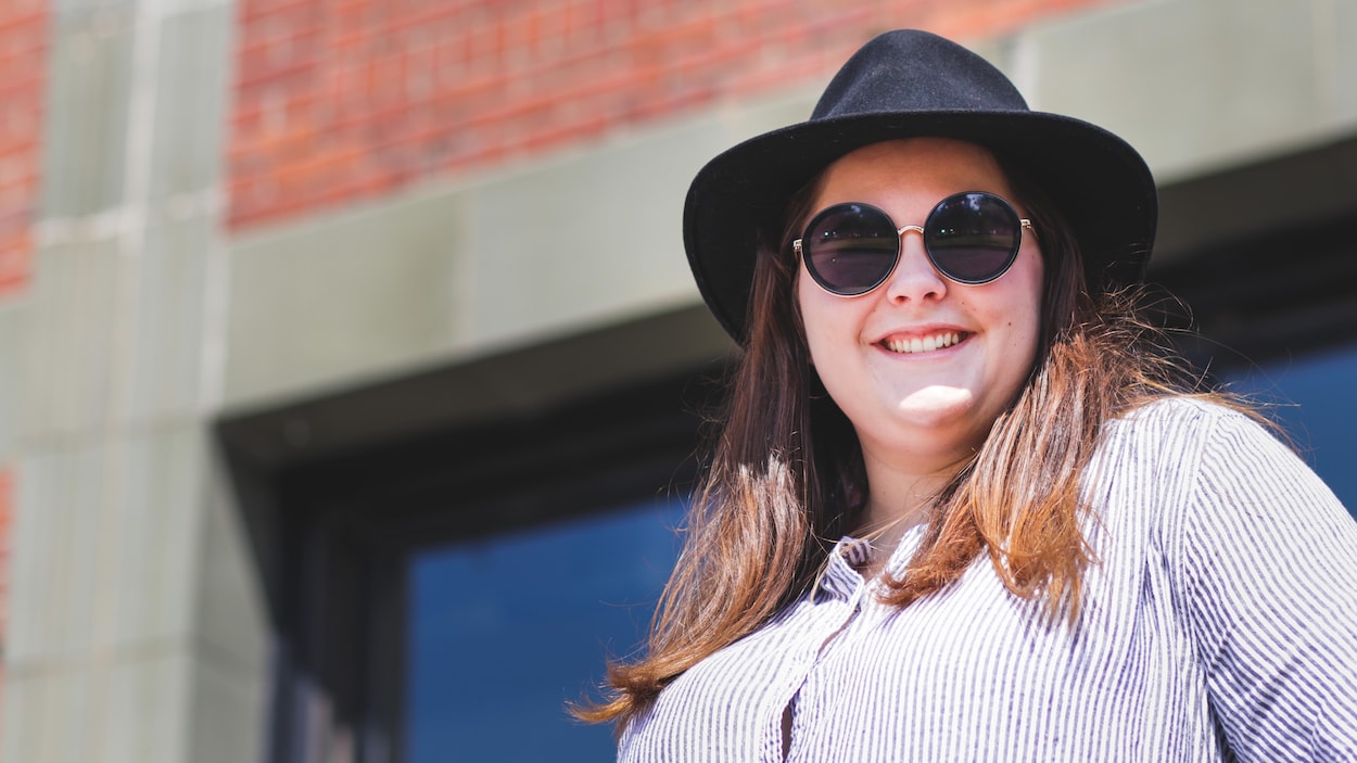 Une jeune femme vêtue d'un chapeau portant des lunettes soleil.