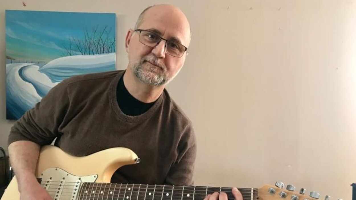 Christopher Giede souriant, en train de jouer de la guitare électrique.