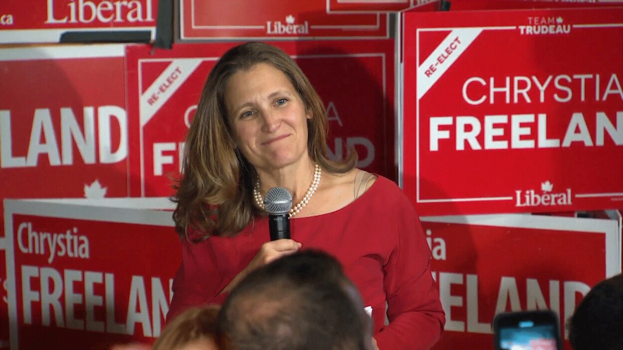 Chrystia Freeland au micro devant des affiches électorales.