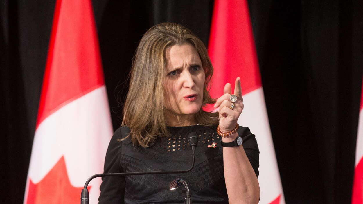 Chrystia Freeland, devant des drapeaux canadiens, affiche une mine sévère et brandit un doigt accusateur. Chrystia Freeland, devant des drapeaux canadiens, affiche une mine sévère et brandit un doigt accusateur.