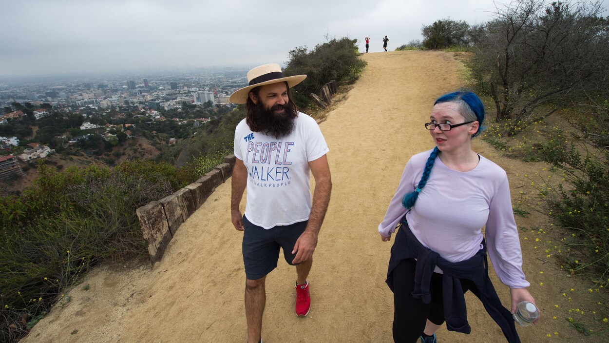 Chuck McCarthy discute avec une cliente alors qu'ils marchent sur un sentier dans les collines d'Hollywood. On peut apercevoir la ville de Los Angeles en arrière-plan. Chuck McCarthy discute avec une cliente alors qu'ils marchent sur un sentier dans les collines d'Hollywood. On peut apercevoir la ville de Los Angeles en arrière-plan.