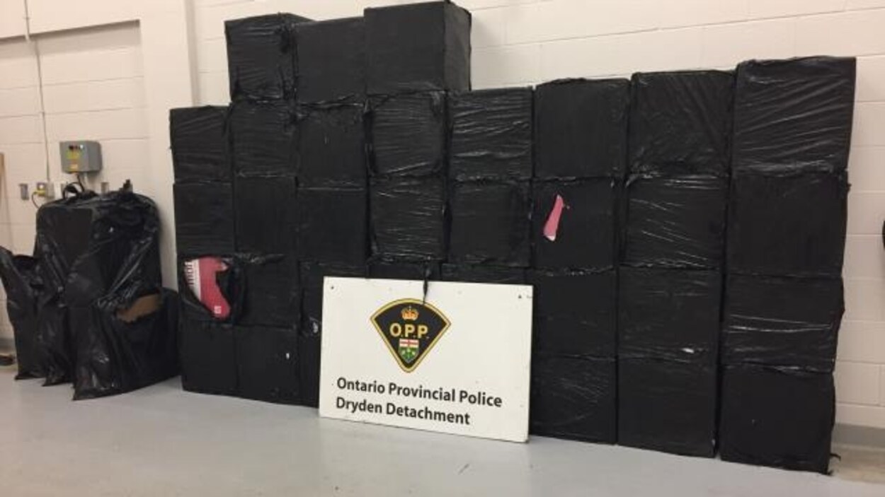 Des caisses enveloppées dans des sacs à poubelle et enlignées sur un mur avec une pancarte de la police devant
