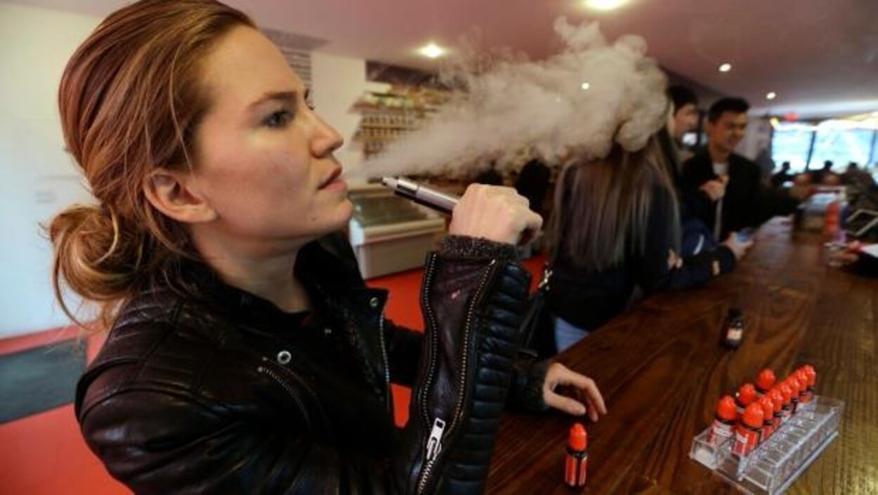 Une femme fume une cigarette électronique