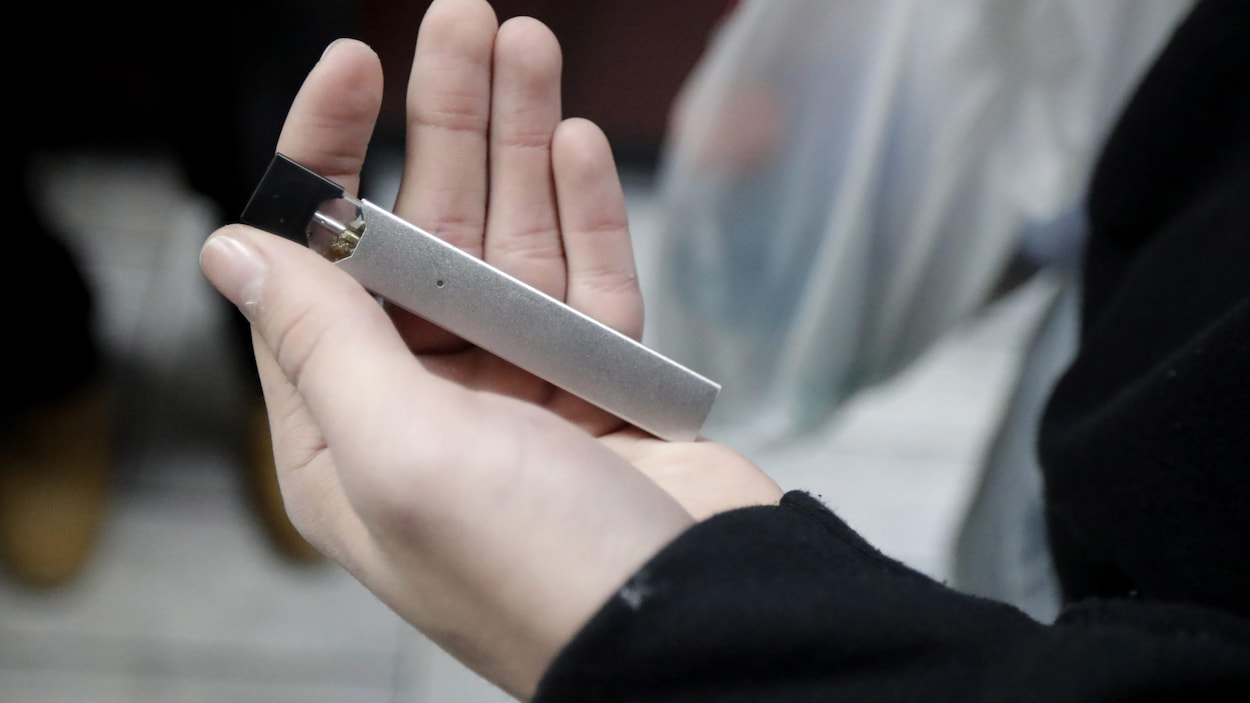 Une personne tient une cigarette électronique dans ses mains.
