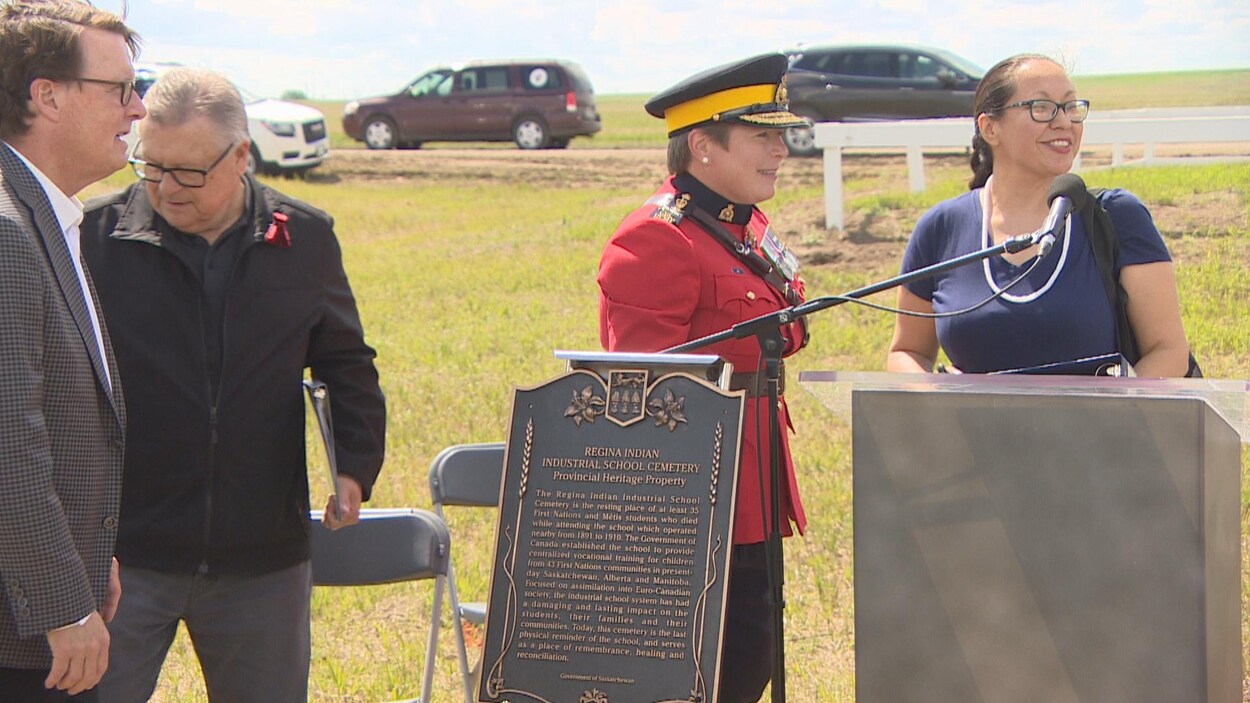 Plusieurs personnes sont debout près d’une plaque qui reconnaît le terrain du cimetière de l’École industrielle autochtone de Regina comme site patrimonial provincial.